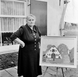 126620 Portret van de naïeve schilder mw. A. Zomer met één van haar olieverfschilderijen bij haar woning naast het ...
